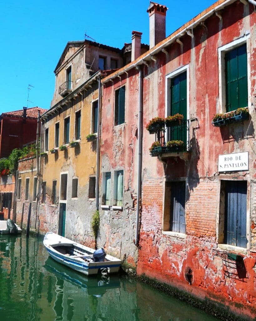 Colourful rustic red and yellow buildings set against a Venetian canal.