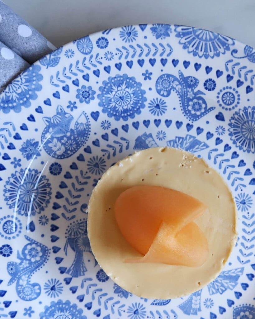 Vegan melon cheesecake on a blue patterned plate, birds eye view