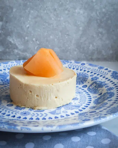 Side on vegan melon cheesecake on a blue patterned plate