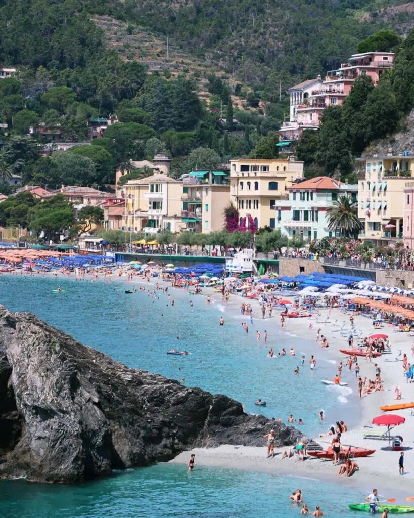 The beach at Monterosso Al Mare lined with pastel coloured buildings.