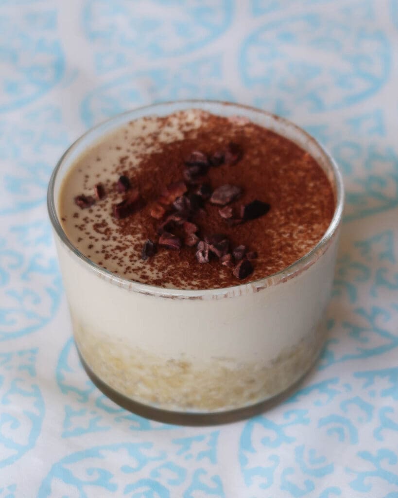 Round glass dessert dish of a layered raw vegan tiramisu