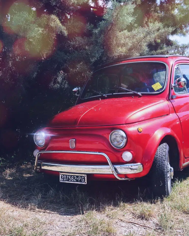 Red Fiat 500 parked on the grass in Italy