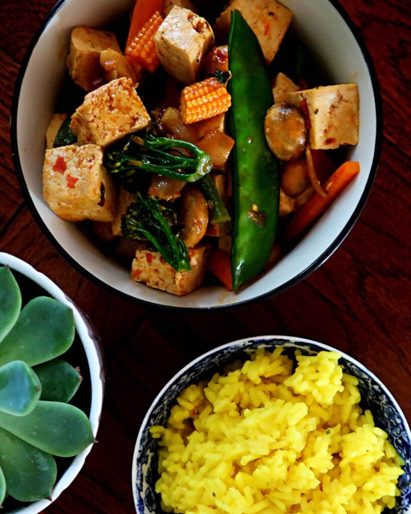 Overhead shot of a Sichuan Chilli Claypot tofu curry and bowl of yellow saffron rice