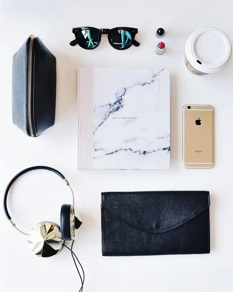 Flat lay with headphones, notepad, phone, sunglasses and make up bag
