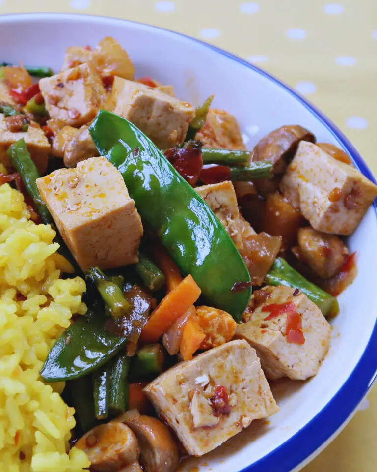 Tofu cubes and fresh green mange tout in a Sichuan tofu curry with a side of yellow saffron rice