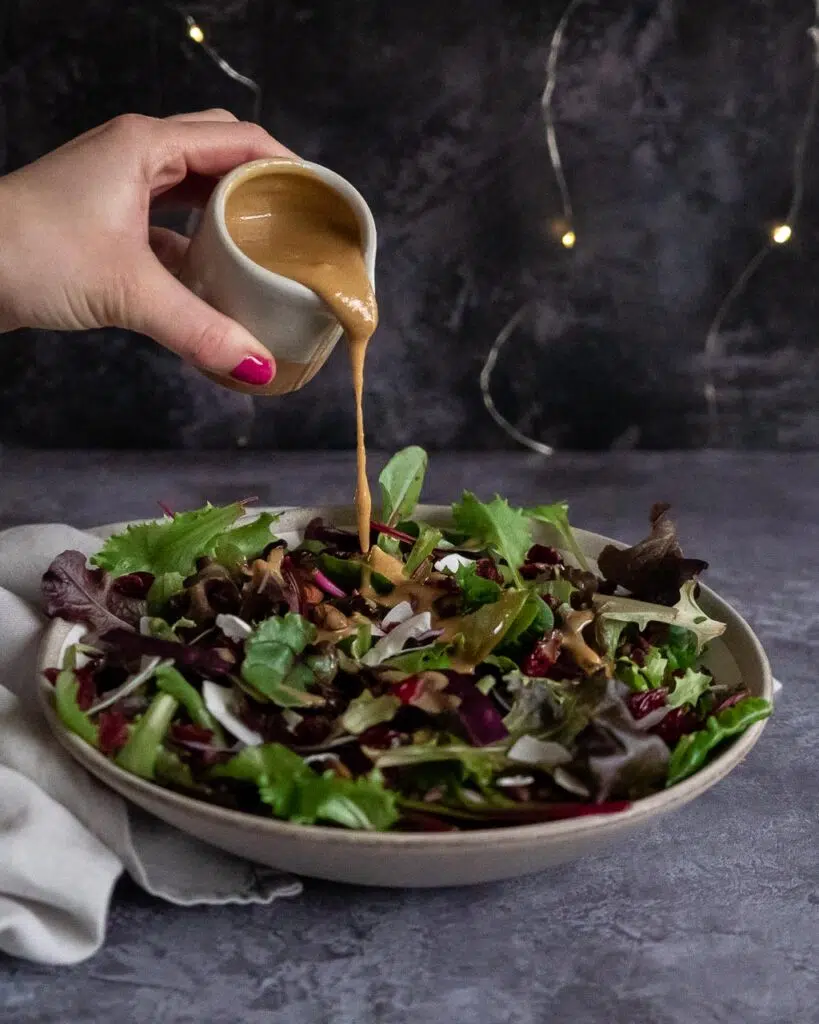 Tahini salad dressing being drizzled over a cranberry and black rice salad