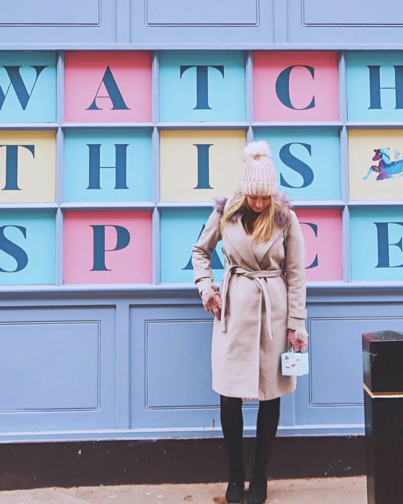 Woman in grey coat stood outside a pastel coloured shop in Covent Garden