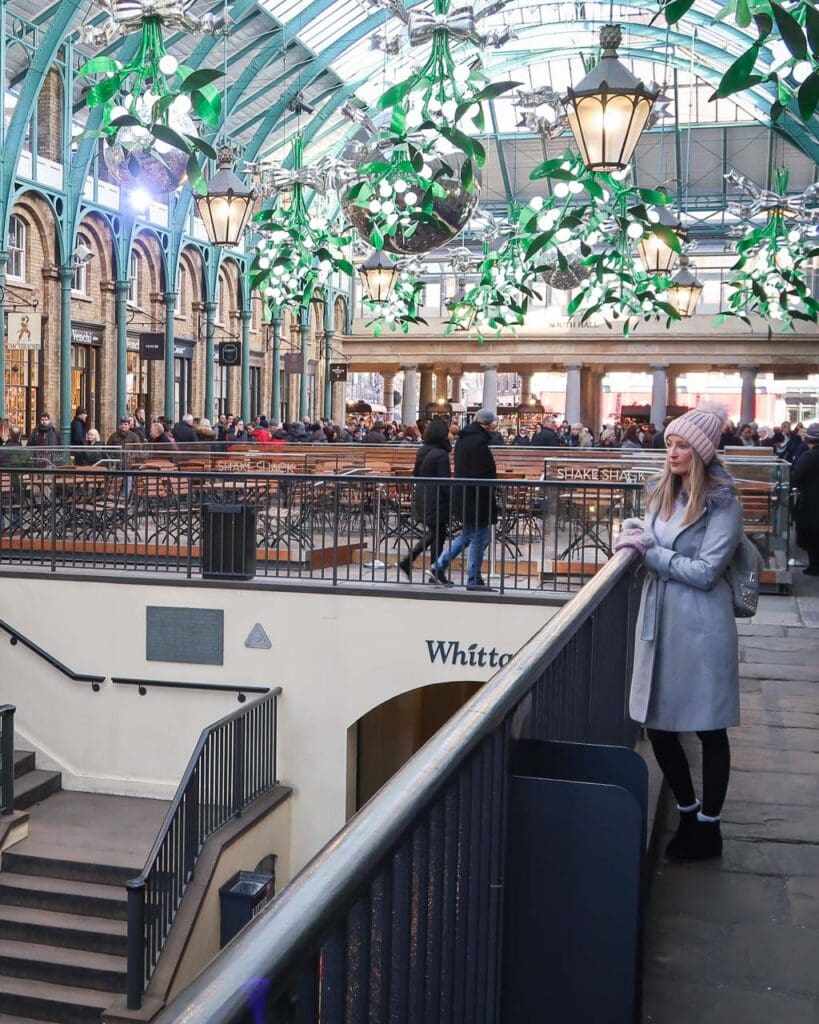 Woman in long grey coat and pink woolly hat admiring Christmas display