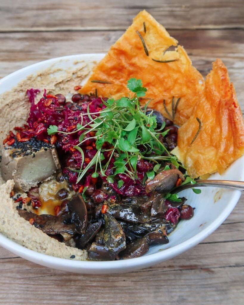 Bowl of vegan food with flat bread, mushrooms, vegan cheese and salad