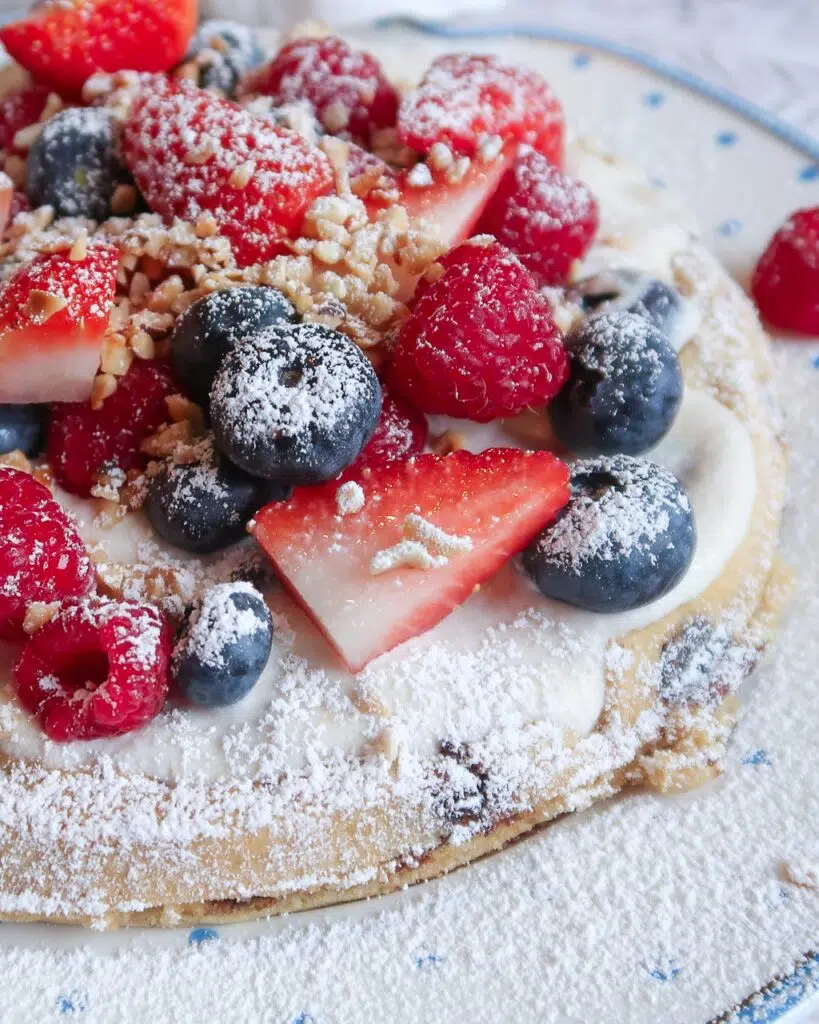Vegan waffle topped with fresh berries, chopped nuts and icing sugar