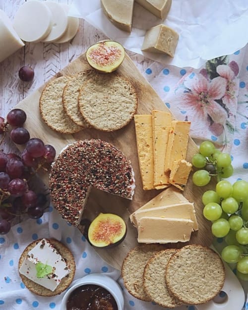 Vegan cheeseboard with cheese slices, rounds, grapes, figs and crackers