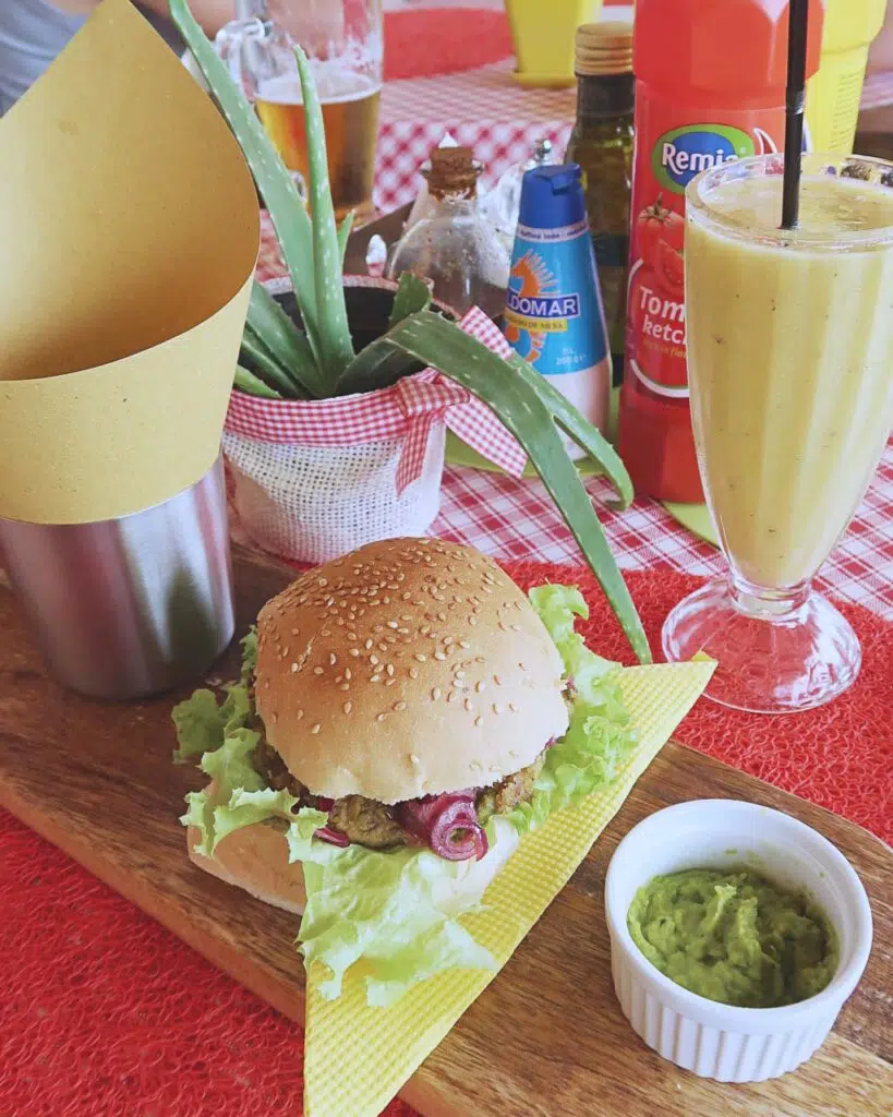 Vegan burger with guacamole and a yellow fruit smoothie