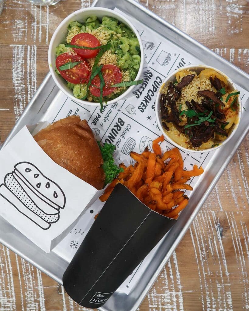 A silver tray of vegan food from By Chloe - fries, burger, Mac n cheese and pasta