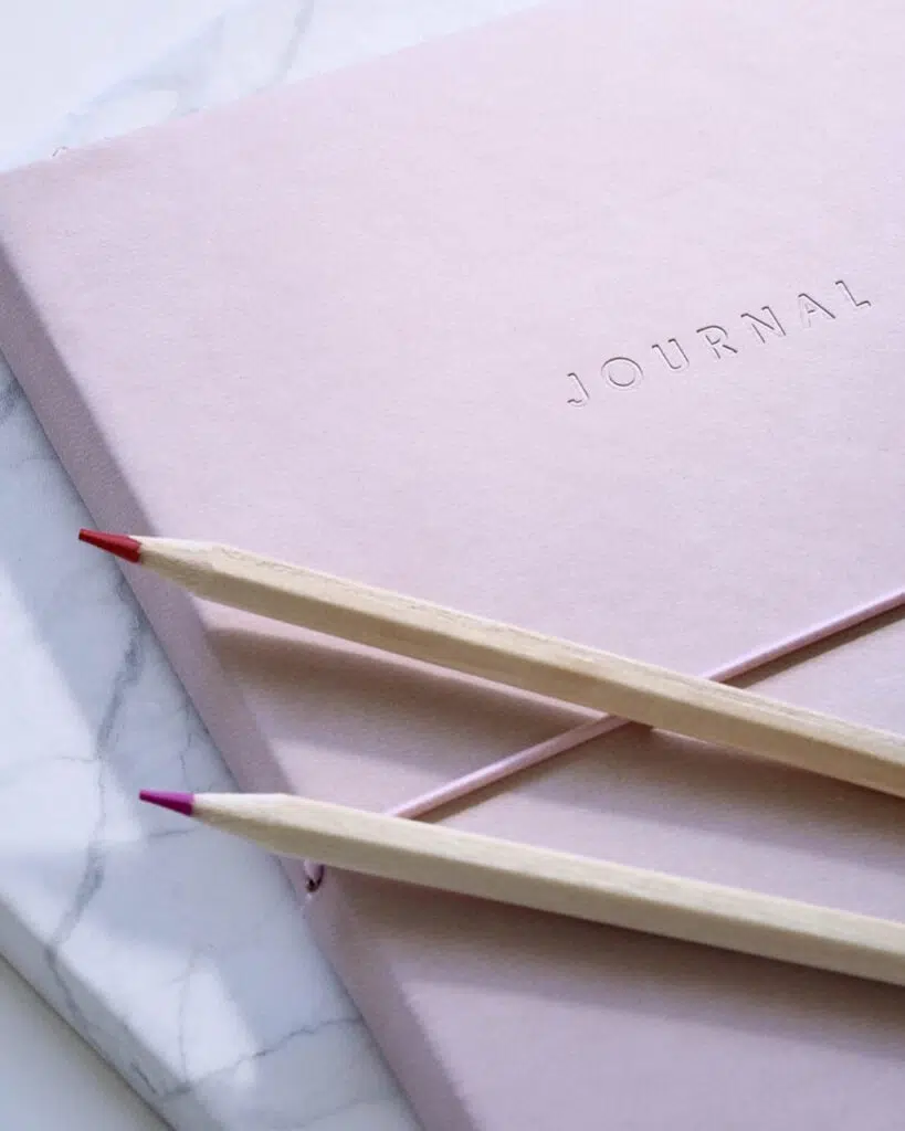 A pink notebook and two pencils