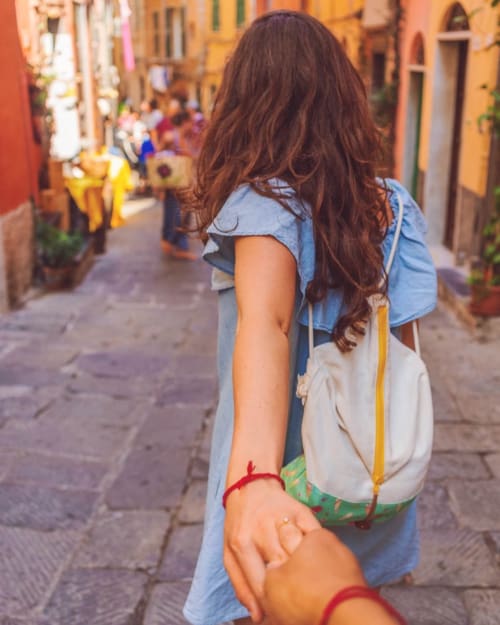 Woman walking down a sunny street holding hand with partner
