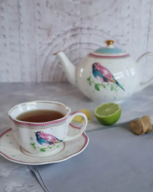 A teacup, saucer and teapot with fresh lime and ginger