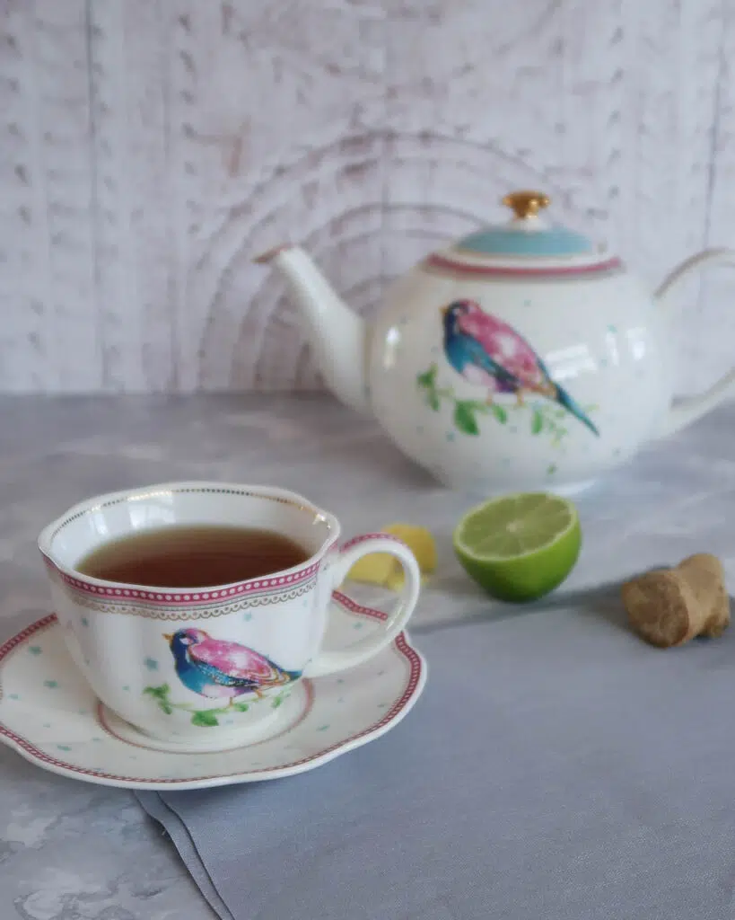 A teacup, saucer and teapot with fresh lime and ginger