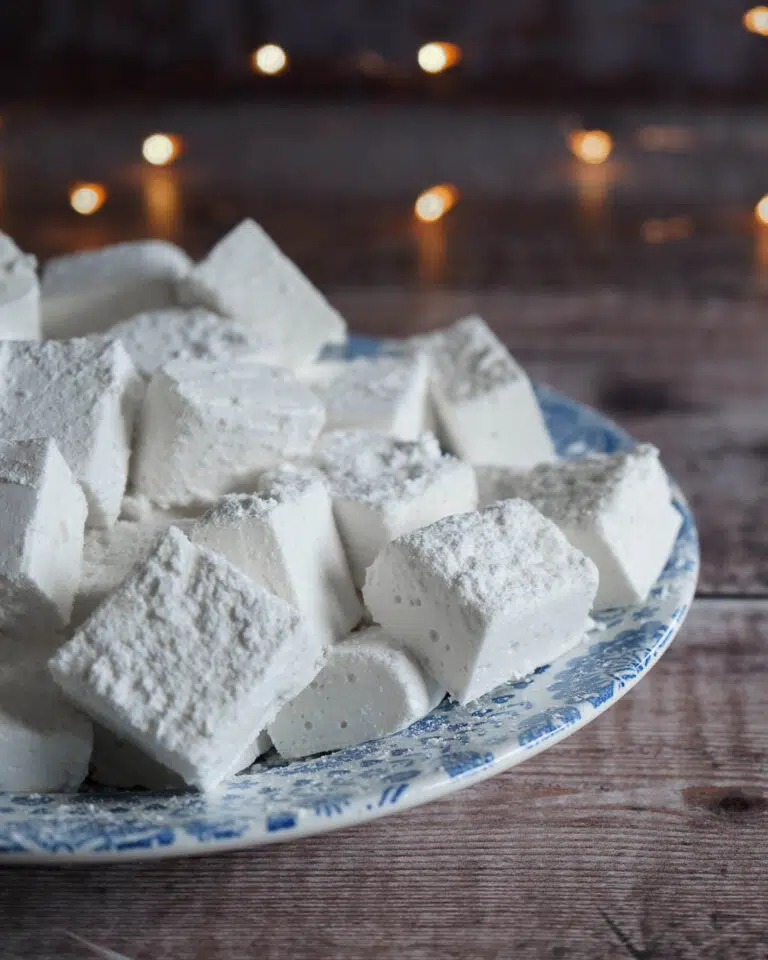 A plate of fluffy vegan marshmallows dusted in icing sugar