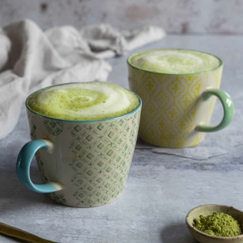 Two cups of vibrant green matcha latte made with frothy oat milk