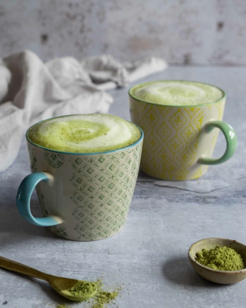 Two cups of vibrant green matcha latte made with frothy oat milk