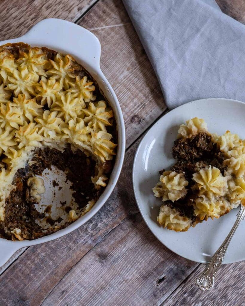 A dish and plate of shepherd's pie with piped mashed potato