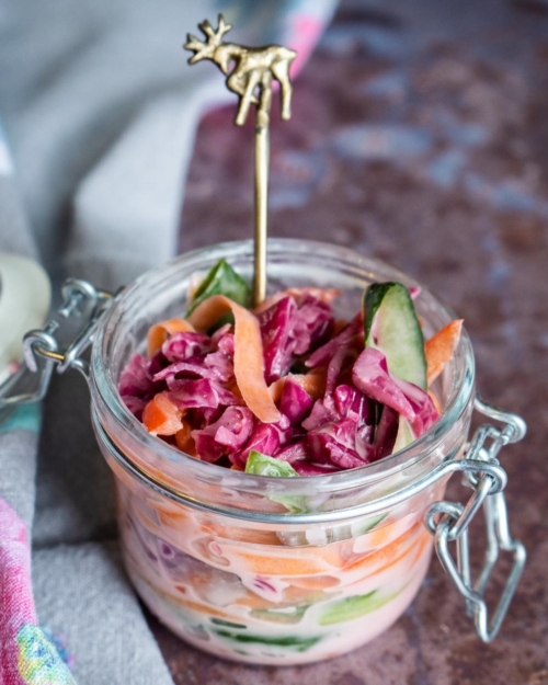 A glass jar of rainbow vegetable ribbons in a vegan slaw