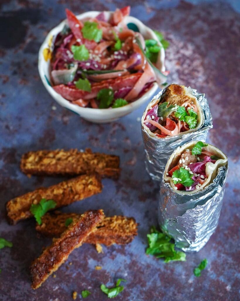 White tortilla wrap with rainbow slaw, a vegan burger and fresh coriander