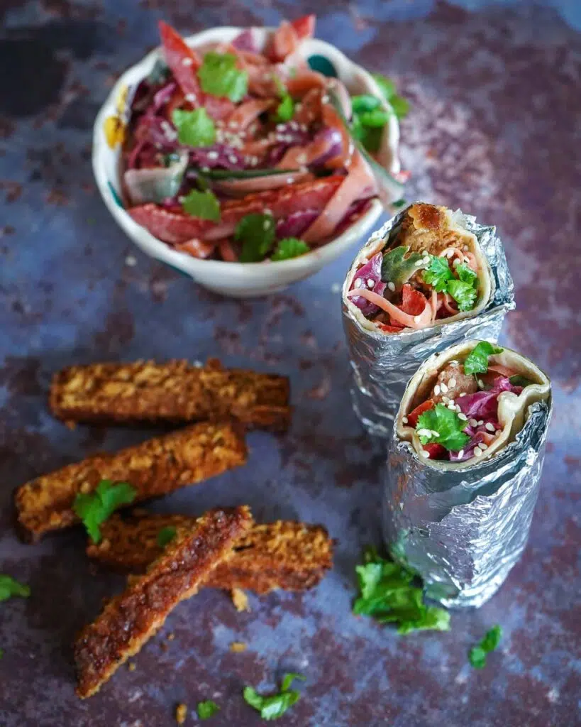White tortilla wrap with rainbow slaw, a vegan burger and fresh coriander