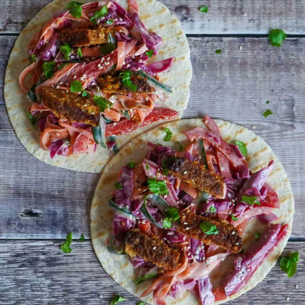 White tortilla wrap with rainbow slaw, a vegan burger and fresh coriander