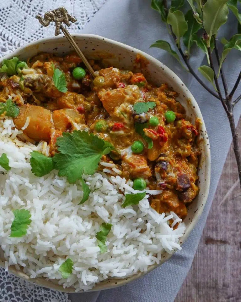 A bowl of vegan korma curry with white rice and a sprinkling of fresh coriander