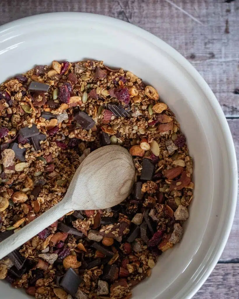 A large mixing bowl of healthy vegan granola with chocolate and dried cranberries