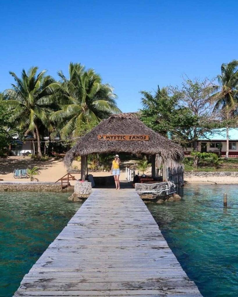 A young woman stood on a boat jetty overlooking the turquoise ocean on the island of Vav'au Tonga