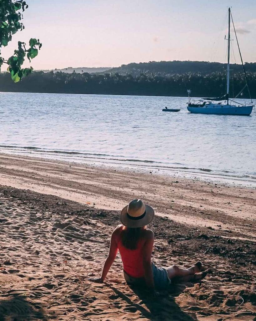 Young woman sat on a beach at sunset in Tonga Vav'au overlooking a calm ocean