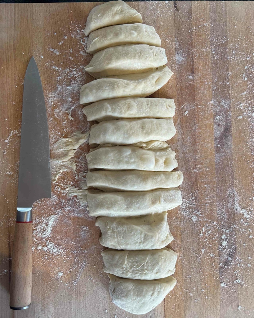 Vegan hot cross bun dough cut into 12 on a chopping board
