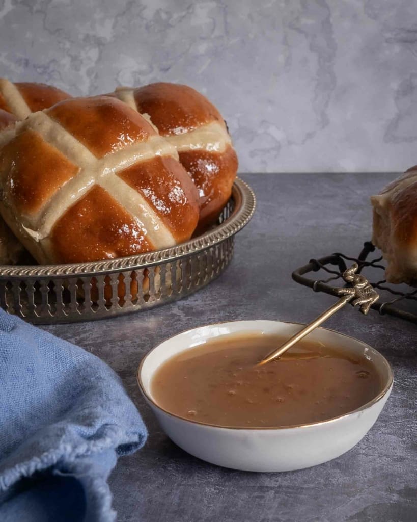 Salted caramel dipping sauce next to a tray of vegan chocolate hot cross buns