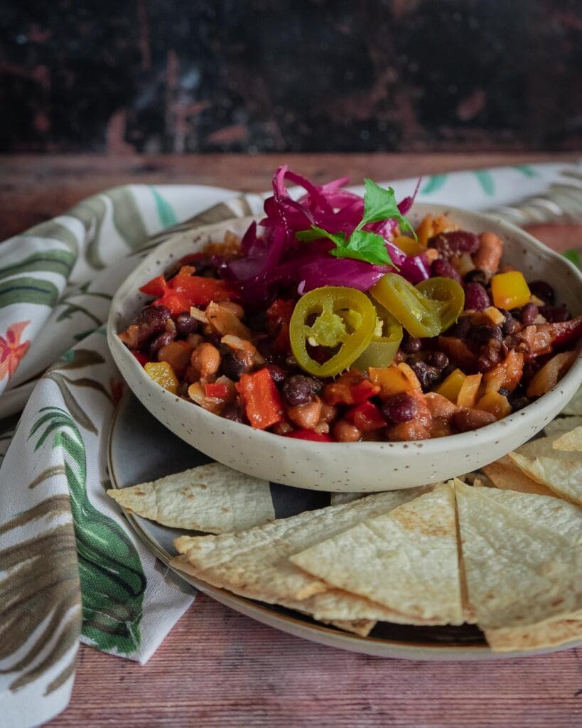 A bowl of black bean chilli with pickled red onions and jalapeño slices