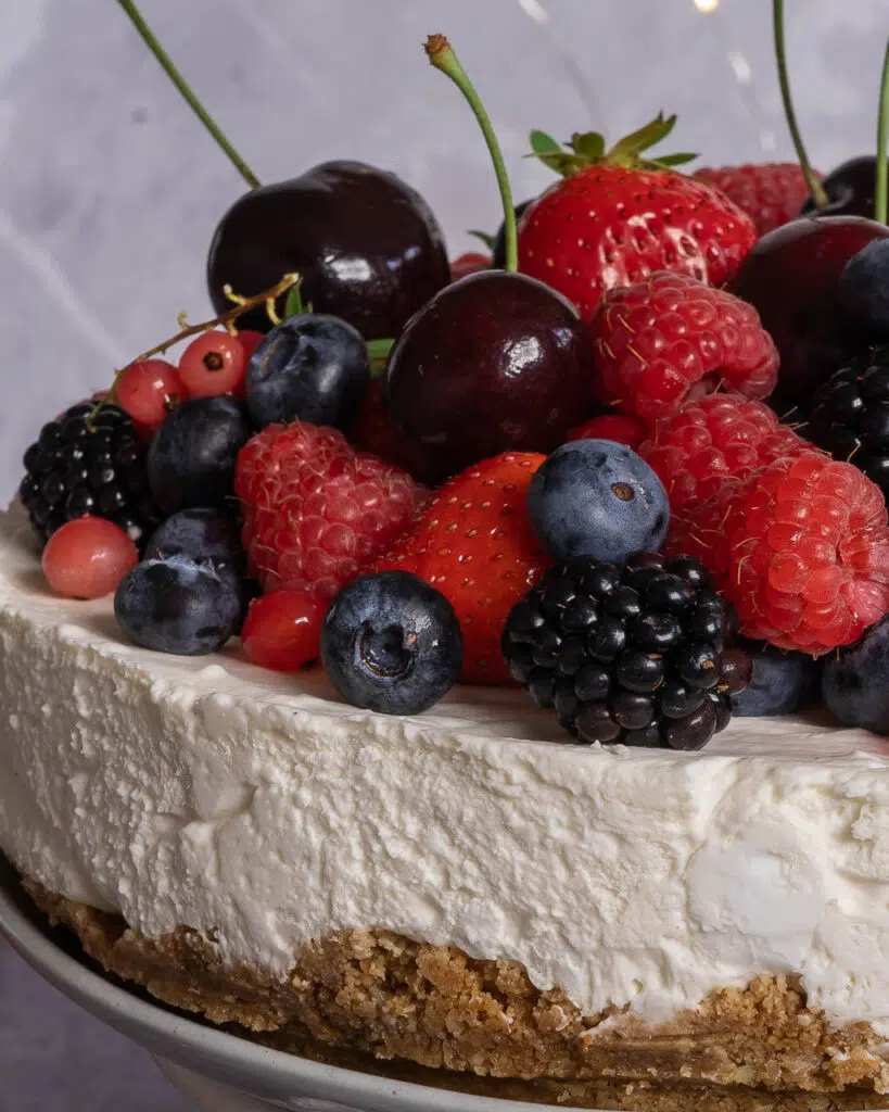 Close up of a vegan no bake cheesecake, piled high with fresh berries