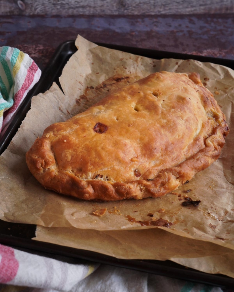 A golden vegetable pasty on a baking tray
