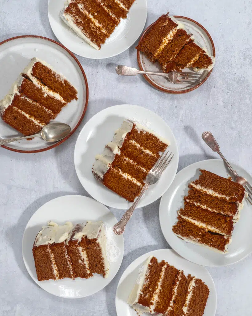 Chunky slices of 4 layer vegan gingerbread cake laid out on multiple plates on a table top