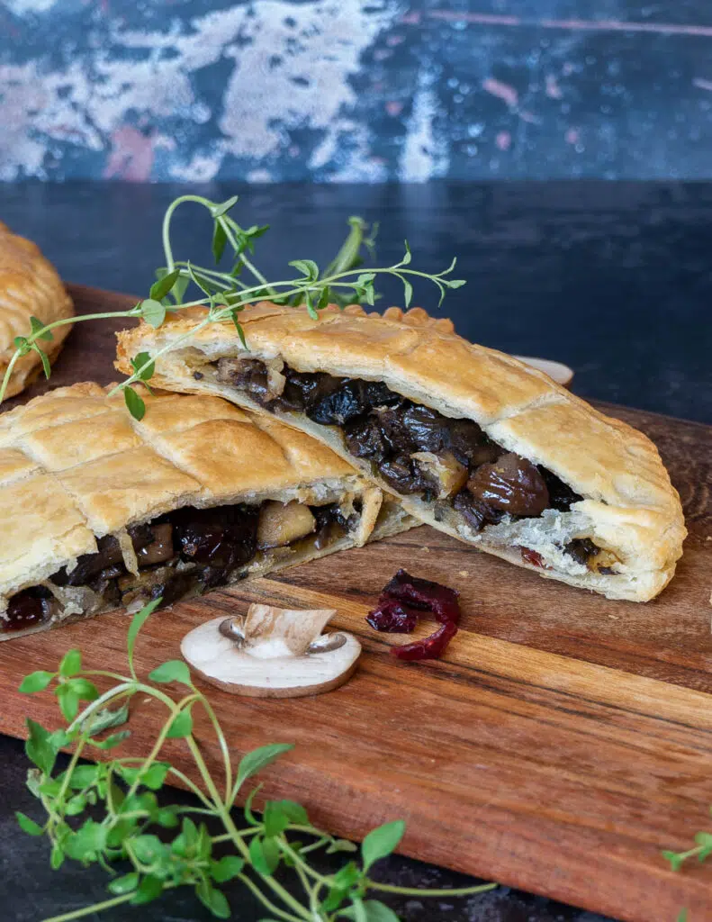 Vegan mushroom pies cut in half revealing a filling made with wild mushrooms, port soaked cranberries, chestnuts and cranberry sauce