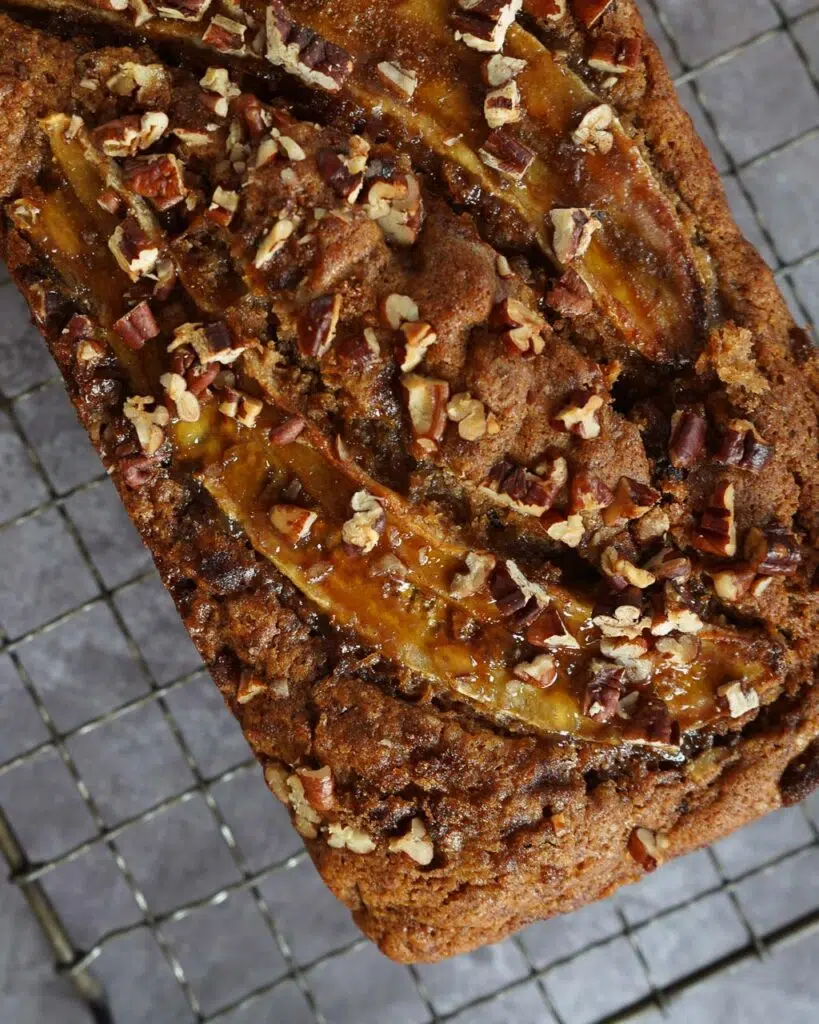 A vegan banana bread topped with caramelised banana slices and toasted chopped nuts
