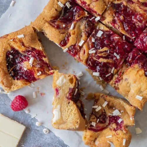 Top down photo of vegan blondies with fresh raspberries, white chocolate and raspberry jam swirled over the top.