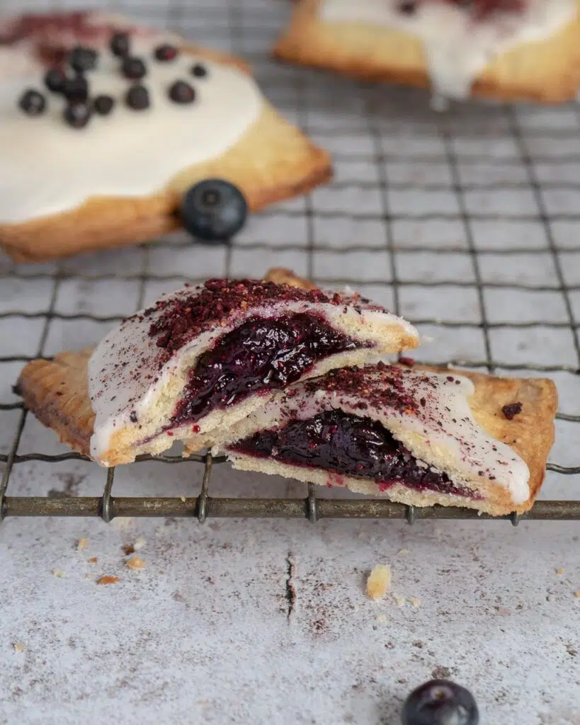 A blueberry vanilla vegan pop tart on a cooling rack, cut in half to expose the jammy centre