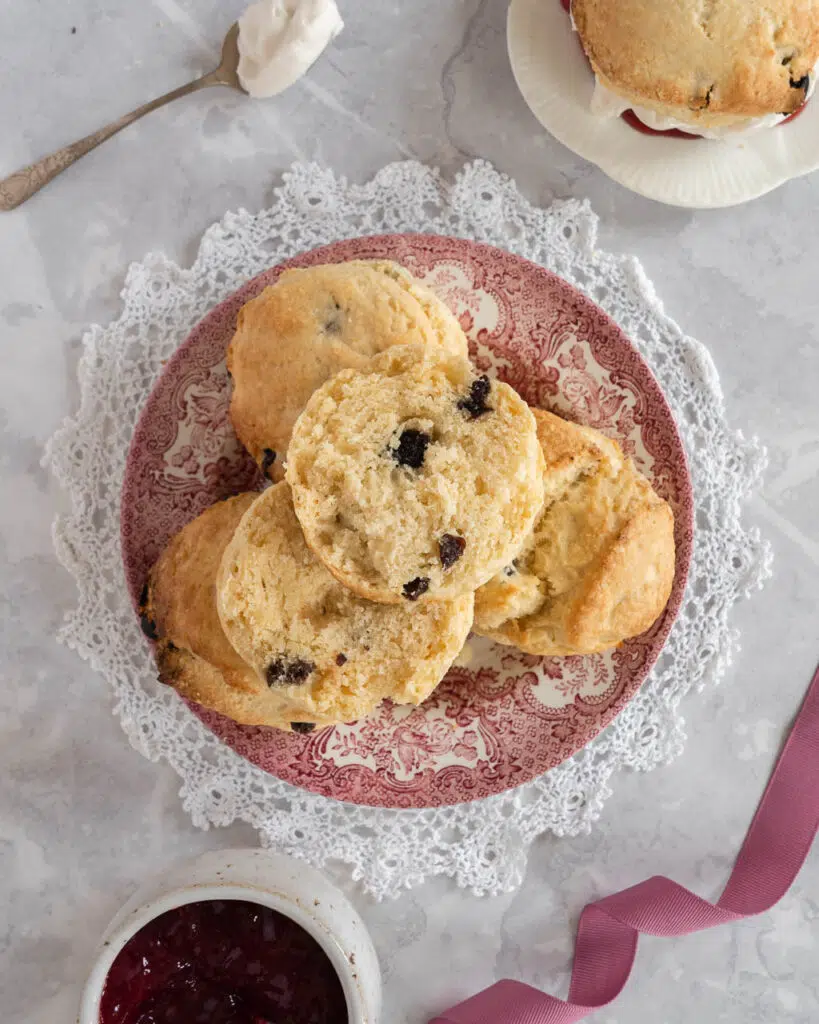 A top down photo of a plate of vegan scones, the top one cut in half to reveal