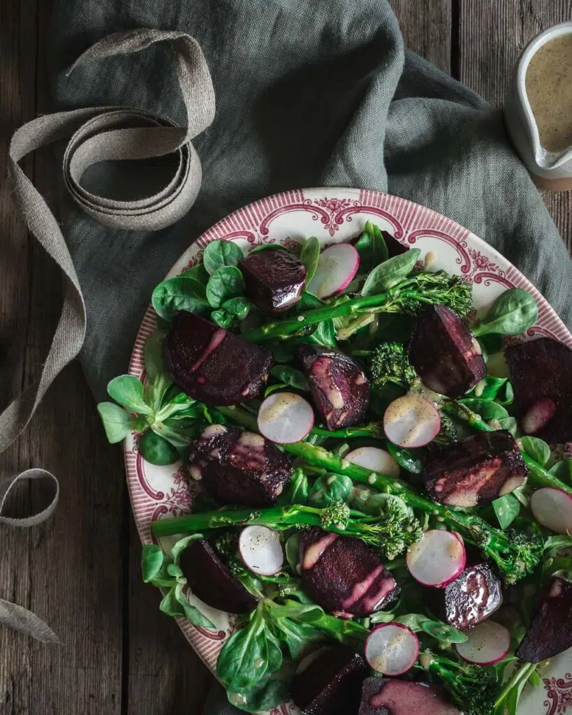 A pretty pink and white platter of roasted tenderstem broccoli and beetroot drizzled in a vegan maple mustard salad dressing