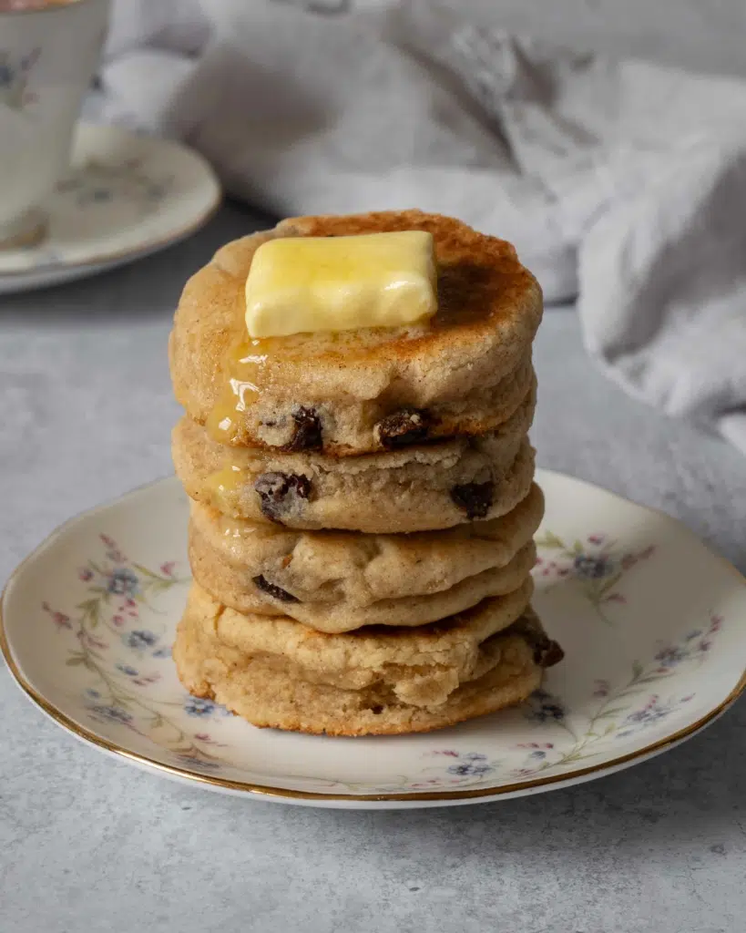 A stack of chunky round vegan welsh cakes studded with juicy sultanas and topped with melting vegan butter