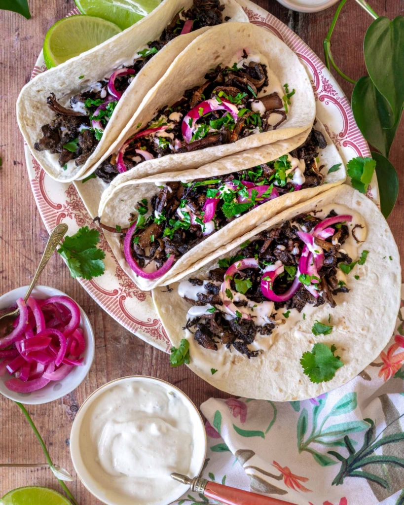 Colourful shredded mushroom carnitas in a soft tortilla with pickled red onions and fresh coriander