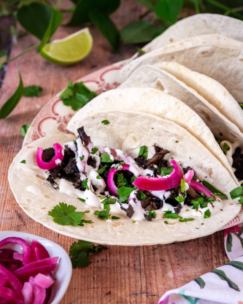 Colourful vegan mushroom carnitas in a soft tortilla with pickled red onions and fresh coriander