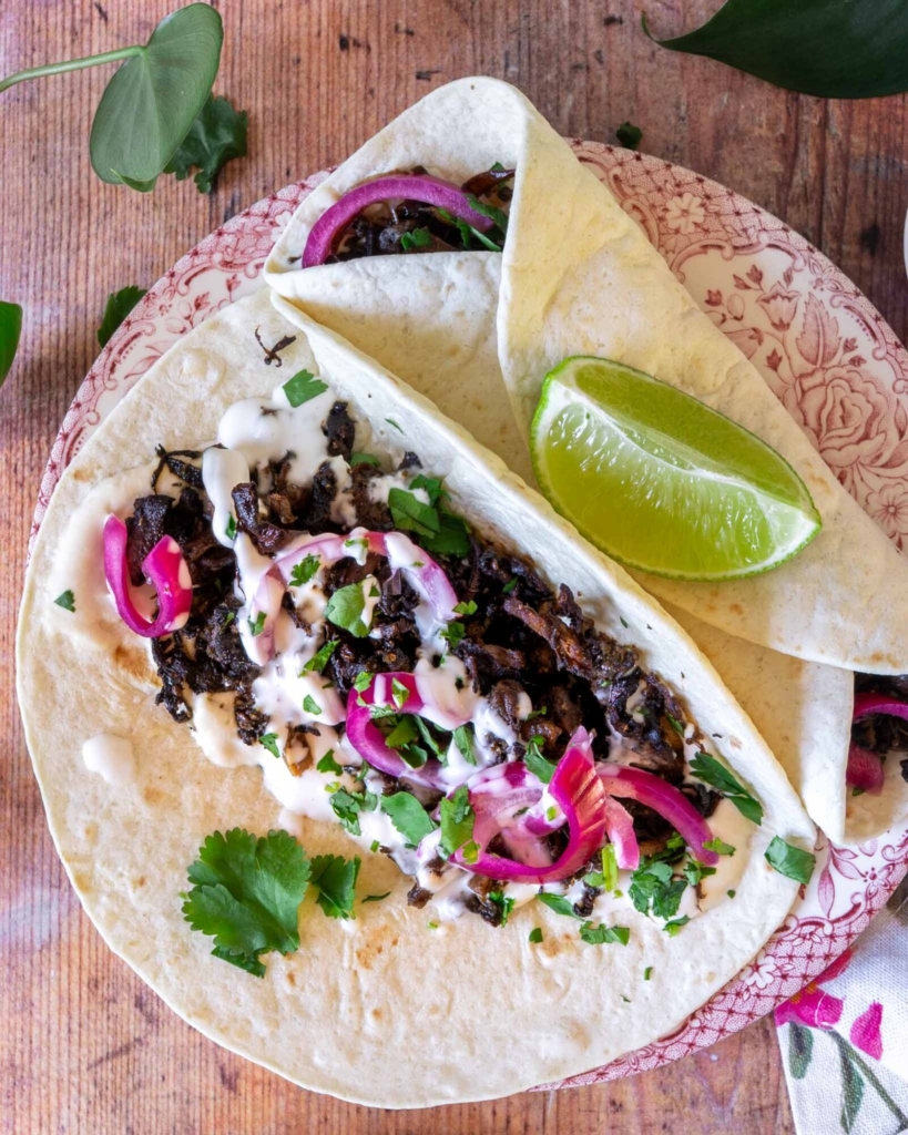 Colourful vegan mushroom carnitas in a soft tortilla with pickled red onions and fresh coriander