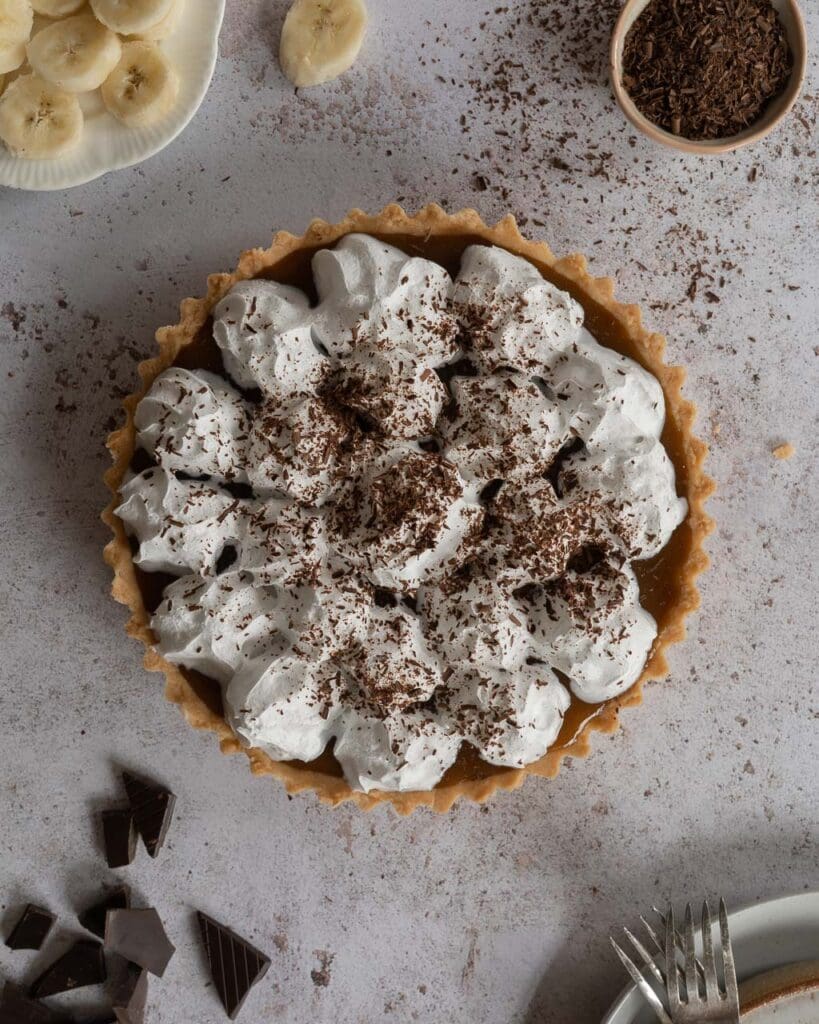A whole vegan Banoffee Pie with piped whipped dairy free cream, photographed from above